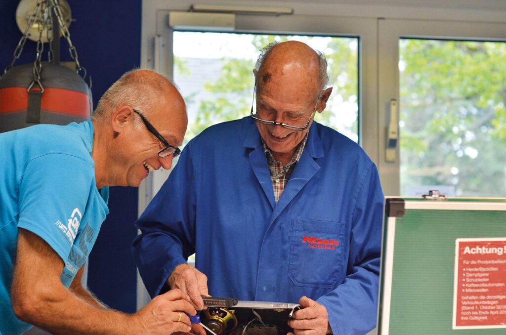 Zwei Männer reparieren ein defektes Gerät, um es wiederverwendbar zu machen.